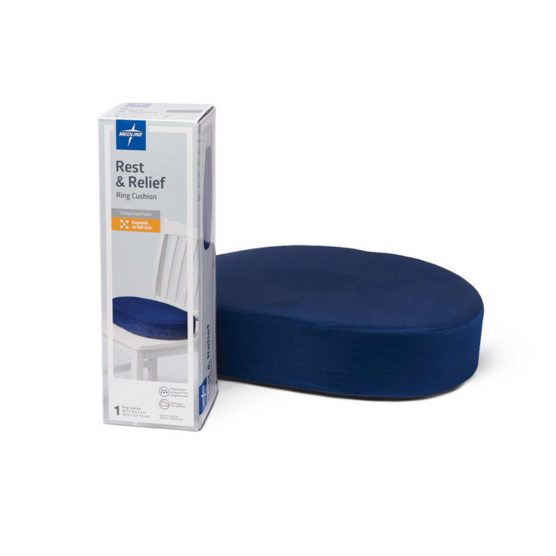 A blue Medline Compressed Foam Ring with a tailbone cutout sits next to its white and blue box, which shows an image of the supportive cushion placed on a chair.